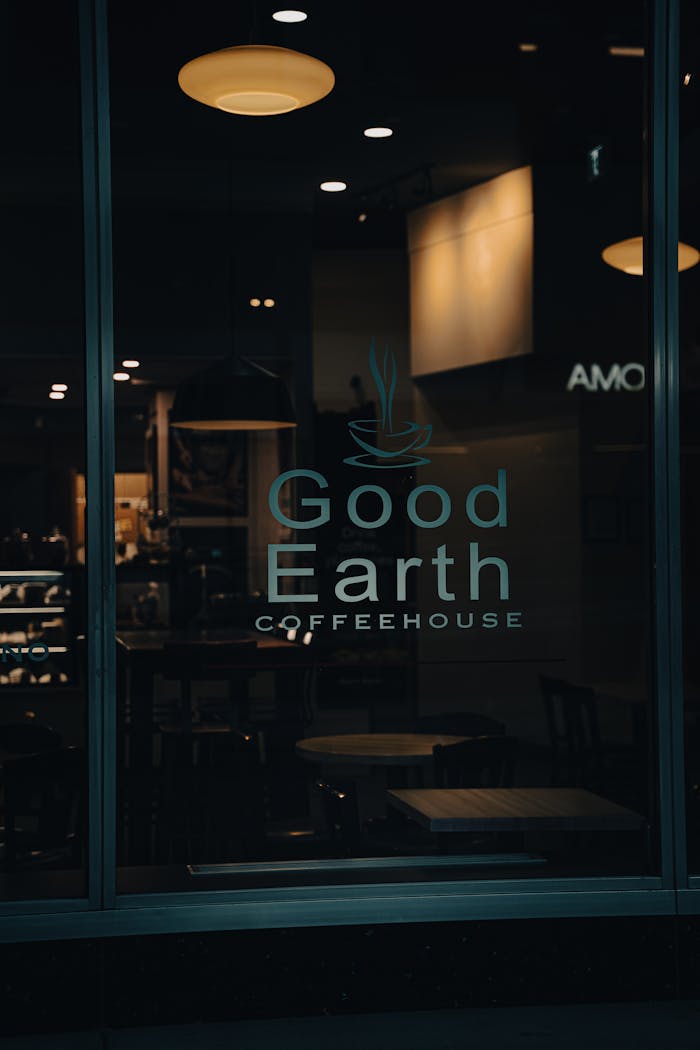 journey Dimly lit coffeehouse window displaying Good Earth Coffeehouse signage.