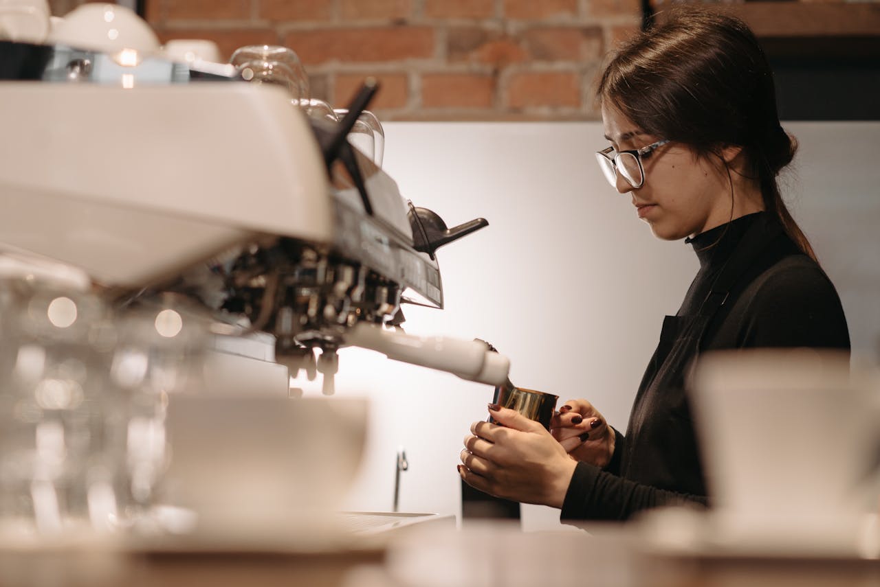 services-03 A focused barista expertly brews coffee using an espresso machine in a cozy cafe setting.